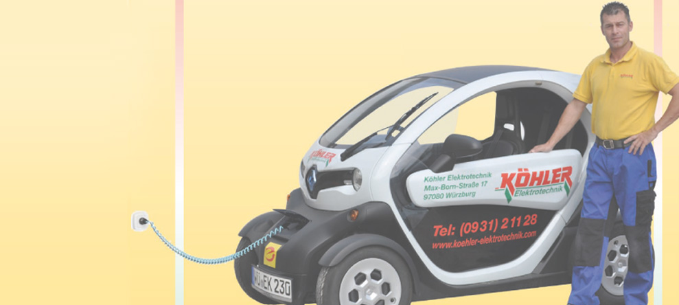 Elektro Köhlers Geschäftsführer Horst Wetzel steht neben kleinem E-Auto, das Werbung seiner Frima trägt und über Kabel mit Steckdose verbunden ist